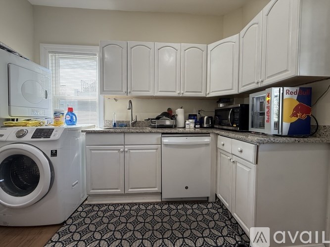 A kitchen with white cabinets and a black and white patterned rug.