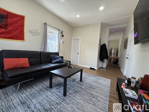 A living room with a black couch and a flag on the wall.
