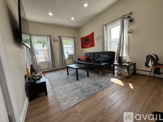 A living room with a black couch and a television on the wall.