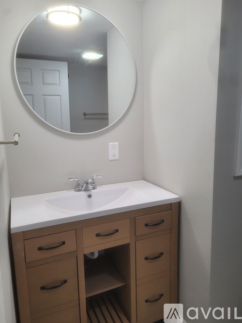 A bathroom with a white sink and a round mirror.