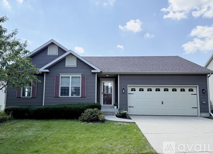 A house with a grey garage door and a brown roof.