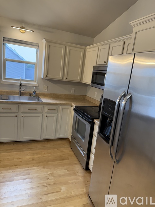 A kitchen with a stainless steel refrigerator and wooden flooring.