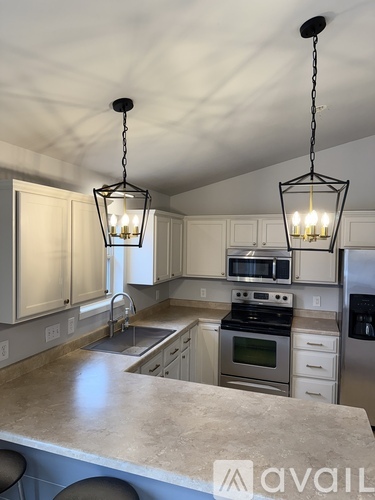 A kitchen with a large island and pendant lights.