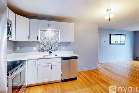 A kitchen with white cabinets and a wooden floor.