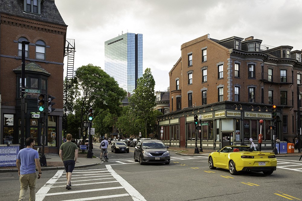 a busy city street with cars and people crossing the street