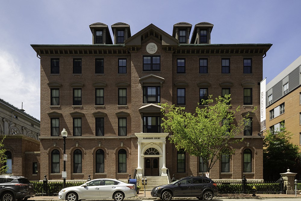 a large brick building with a clock on the front of it and cars parked outside