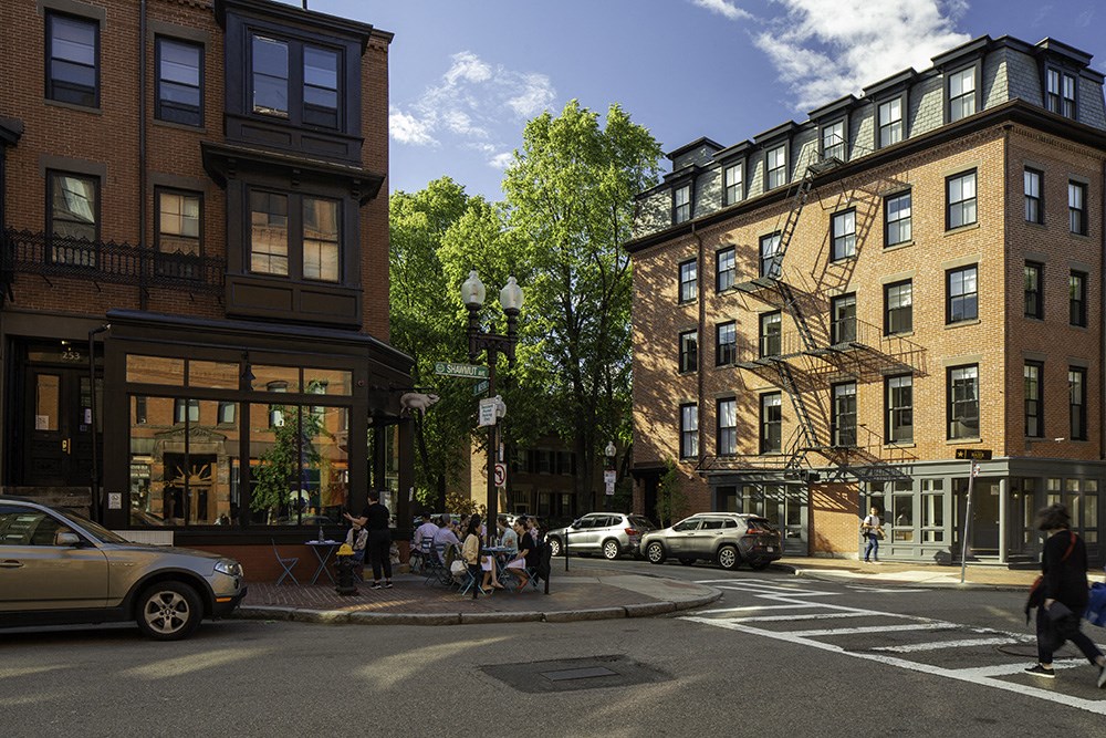 a rendering of a city street with buildings and people crossing the street