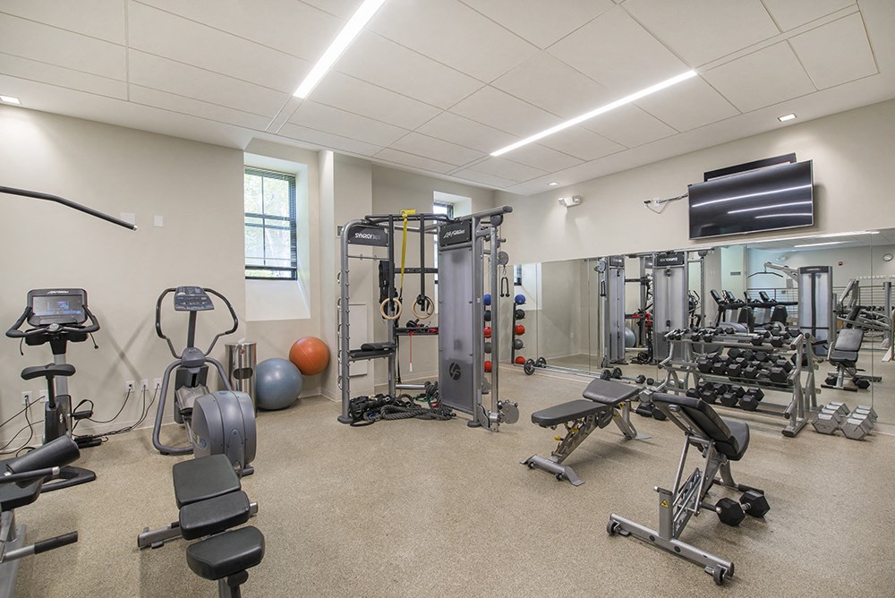 a gym with weights and cardio equipment and a tv