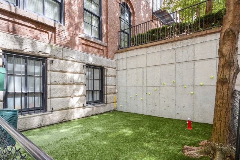 the backyard of a building with green grass and a fire hydrant