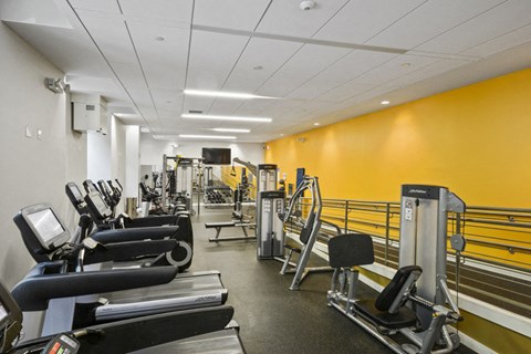 a gym with cardio equipment and weights in a building with yellow walls