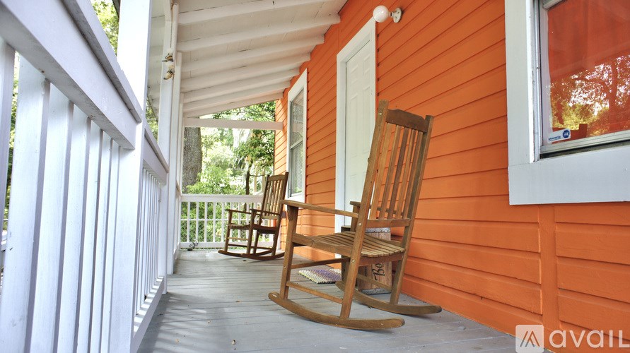 A wooden rocking chair is on a porch.