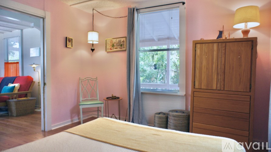 A bedroom with a bed, a chair, a cabinet, and a window.