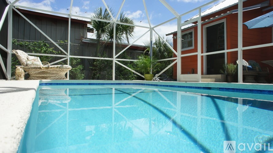 A pool surrounded by a white fence with a house in the background.