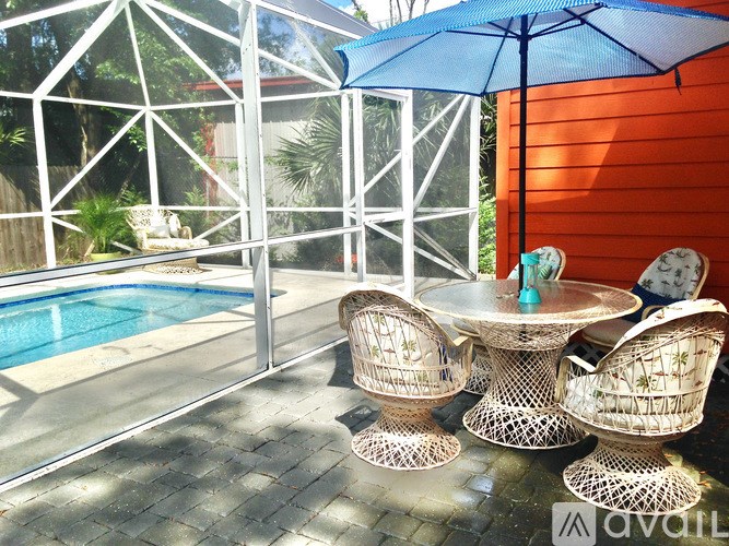 A table with chairs and an umbrella is on a patio.