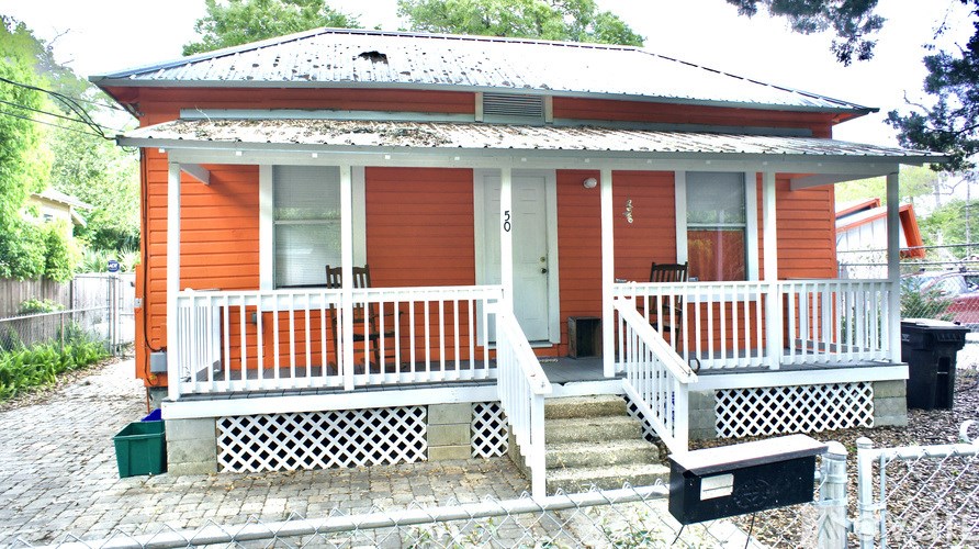 A small orange house with a white porch.