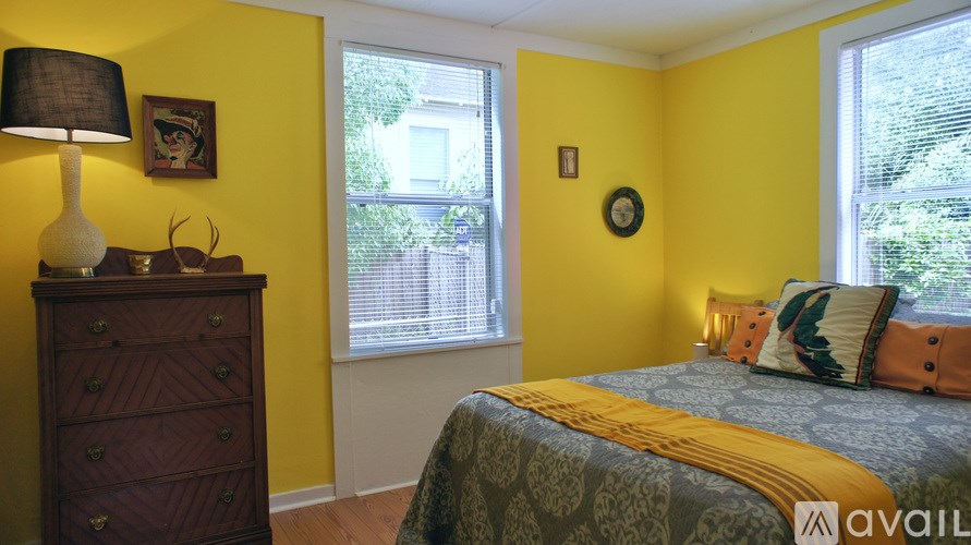 A bedroom with a bed, dresser, and window.