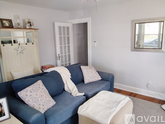 A blue couch with a white pillow and a white blanket on it.