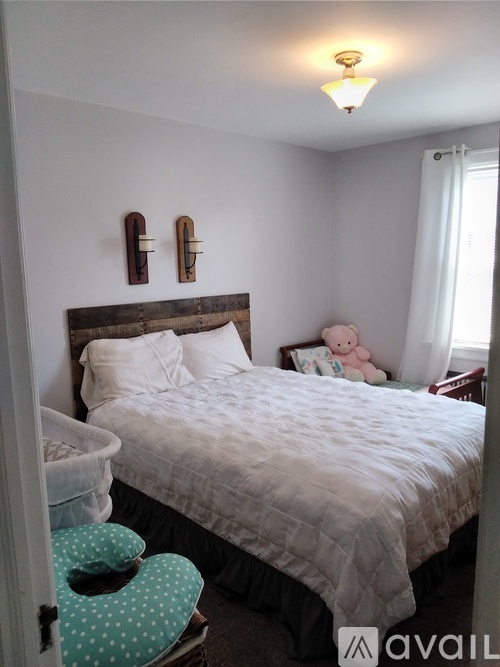 A bedroom with a bed, a teddy bear, and two wall clocks.