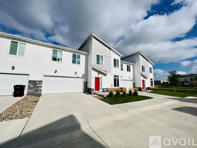 A white house with a red door is in front of a cloudy sky.