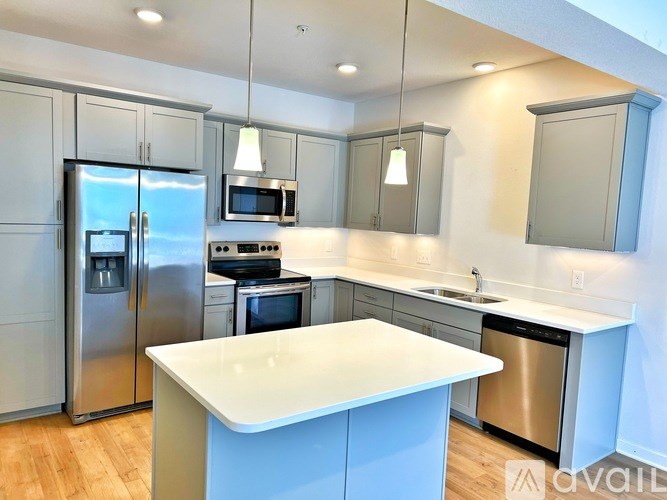 A modern kitchen with a white island and stainless steel appliances.