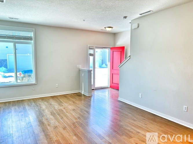 A room with wooden flooring and a red door.