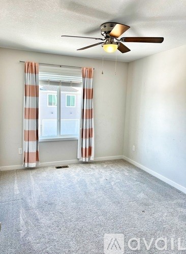 A room with a ceiling fan and a window with striped curtains.