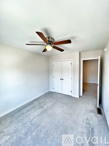A room with a ceiling fan and carpeted floor.