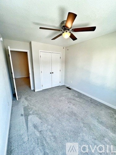 A room with a ceiling fan and carpeted floor.