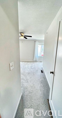 A long hallway with a carpeted floor and a ceiling fan.