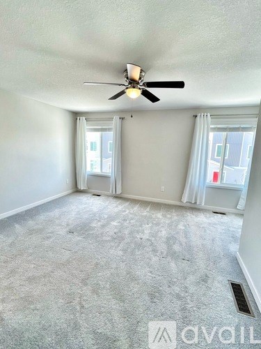 A room with a ceiling fan and carpeted floor.