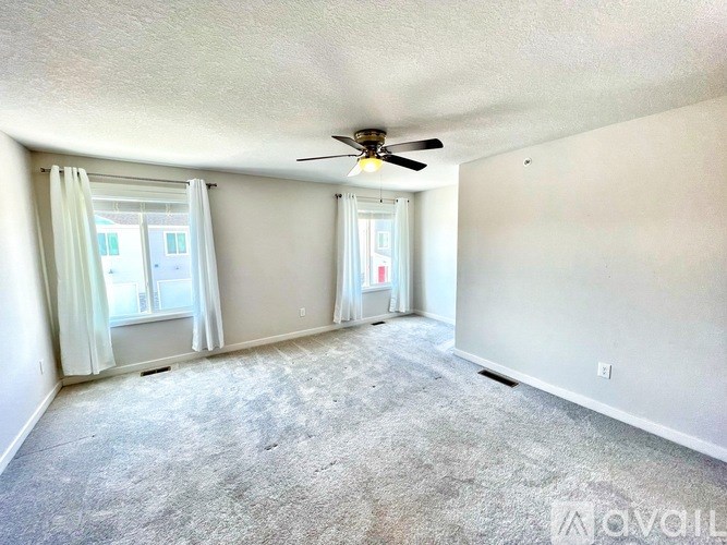 A room with a ceiling fan and carpeted floor.