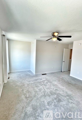 A room with a ceiling fan and carpeted floor.