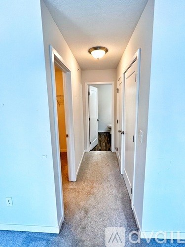 A long hallway with white walls and a carpeted floor.