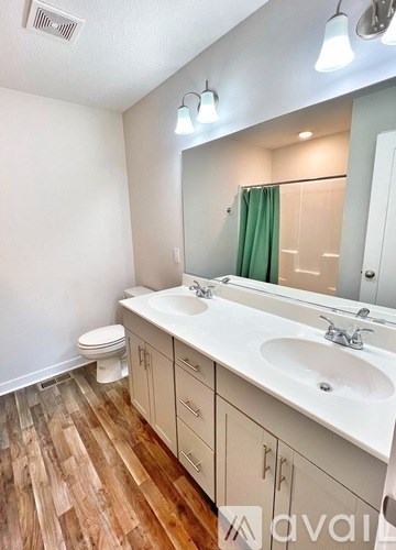 A bathroom with wooden floors and white walls.