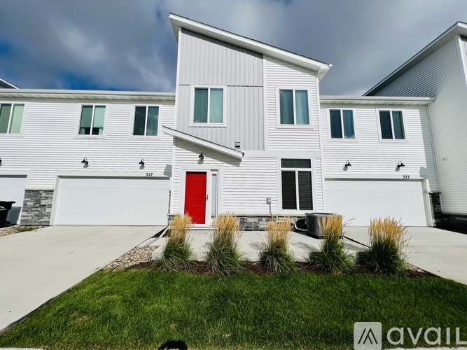 A white house with a red door and a grey garage door.