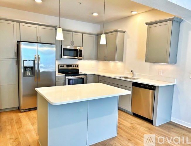 A kitchen with a white island and stainless steel appliances.