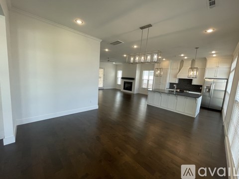 A spacious kitchen and living room with wooden floors and white walls.