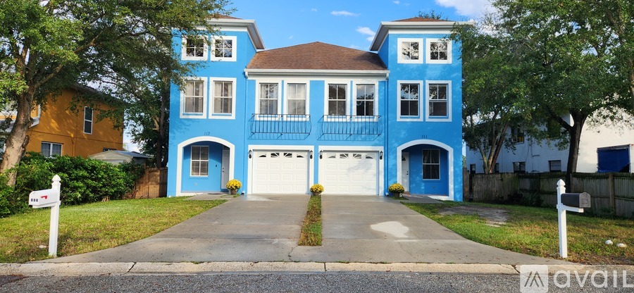 A blue two-story house with a brown roof and a white garage door.