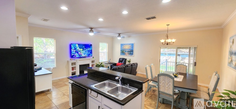 A modern kitchen with a black refrigerator and a television above the island.
