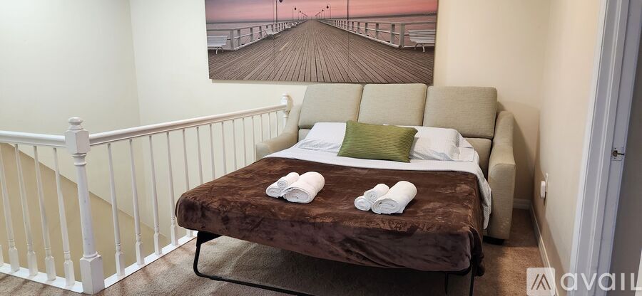 A bedroom with a bed and a picture of a pier on the wall.