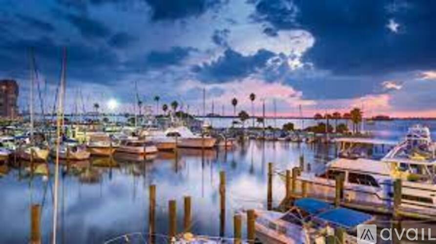 A marina at dusk with boats docked and palm trees in the background.