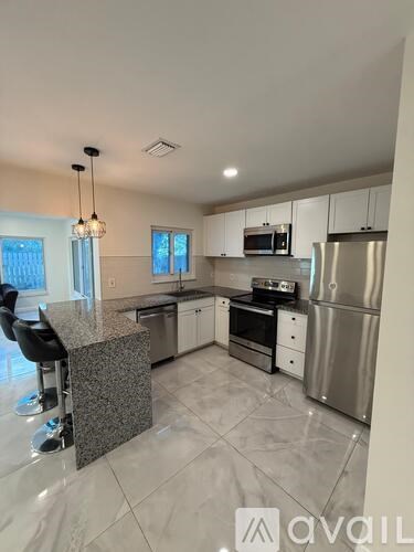 A kitchen with a granite countertop and stainless steel appliances.