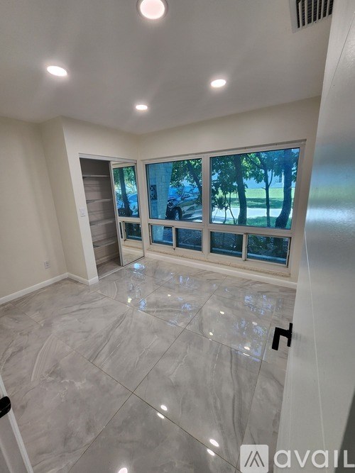 A spacious room with a large window and marble flooring.