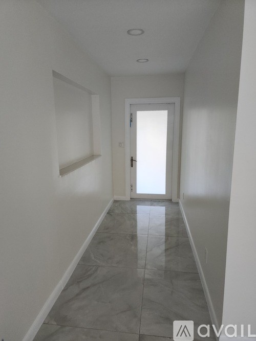 A long hallway with a tiled floor and white walls.