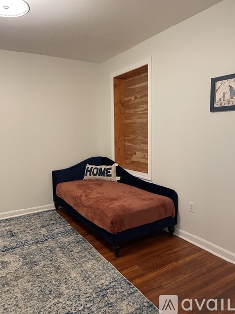 A bedroom with a bed and a rug on the floor.