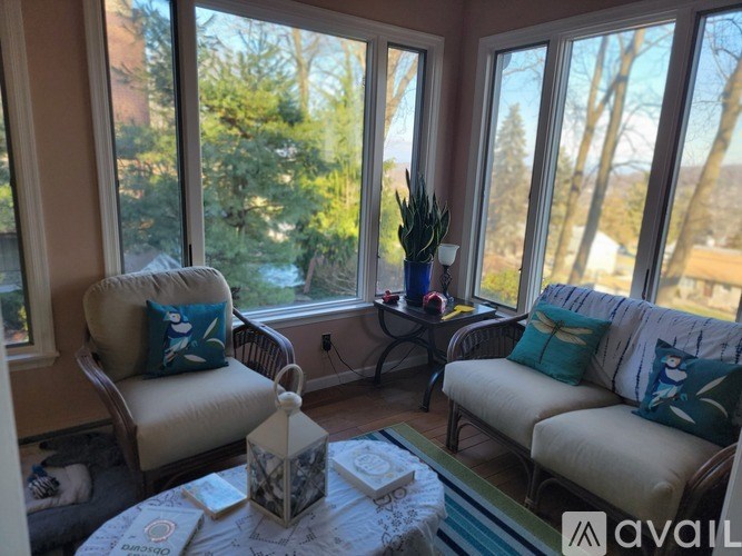 A living room with a sofa, armchair, and a table with a vase and a lantern on it.
