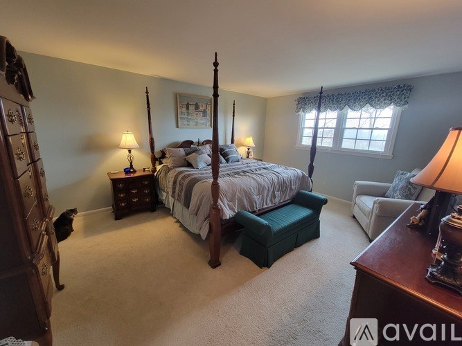 A bedroom with a four poster bed and a cat.