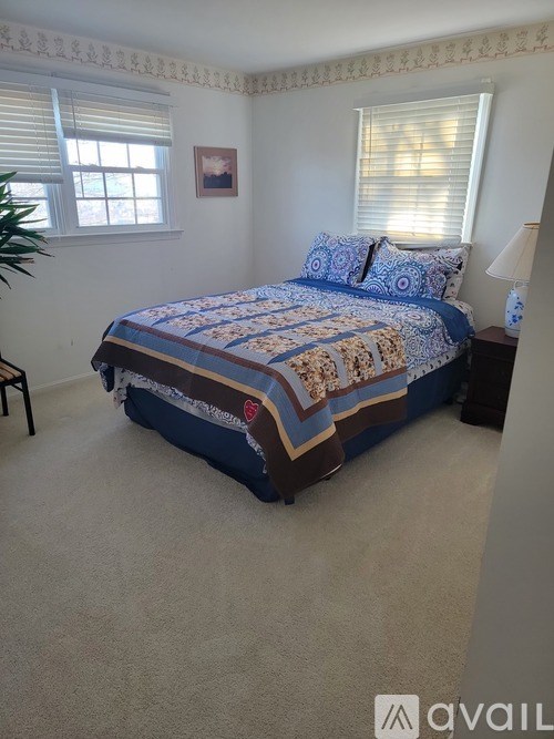 A bedroom with a bed covered in a blue and white quilt.