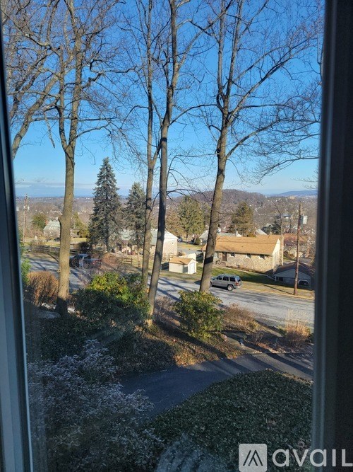 A view from a window looking out at a residential street with houses and trees.