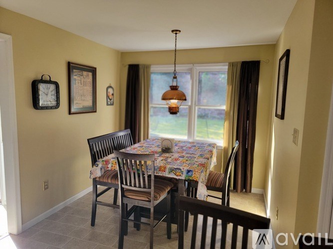 A dining room with a table set for two and a window with curtains.